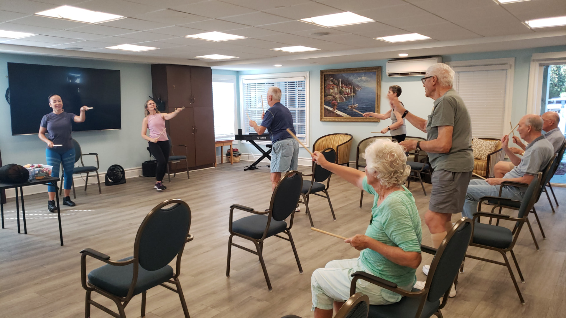 A community room full of participants playing rhythm sticks